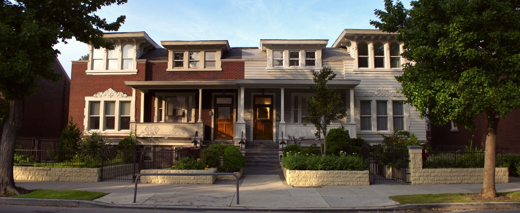 A mixed row of brick and sided two-family houses on the Brooklyn side of the Queens line
