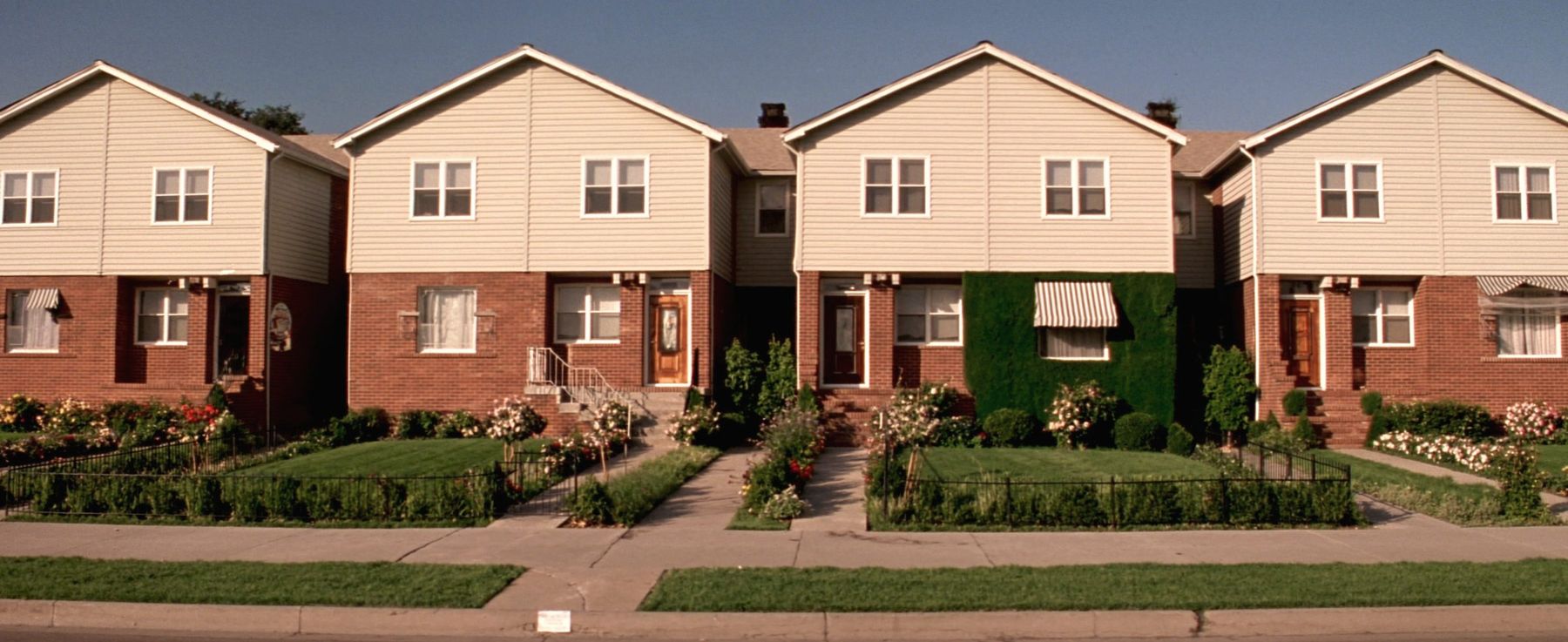 Semi-detached two-family houses with door awnings and small front gardens in Glendale, Queens