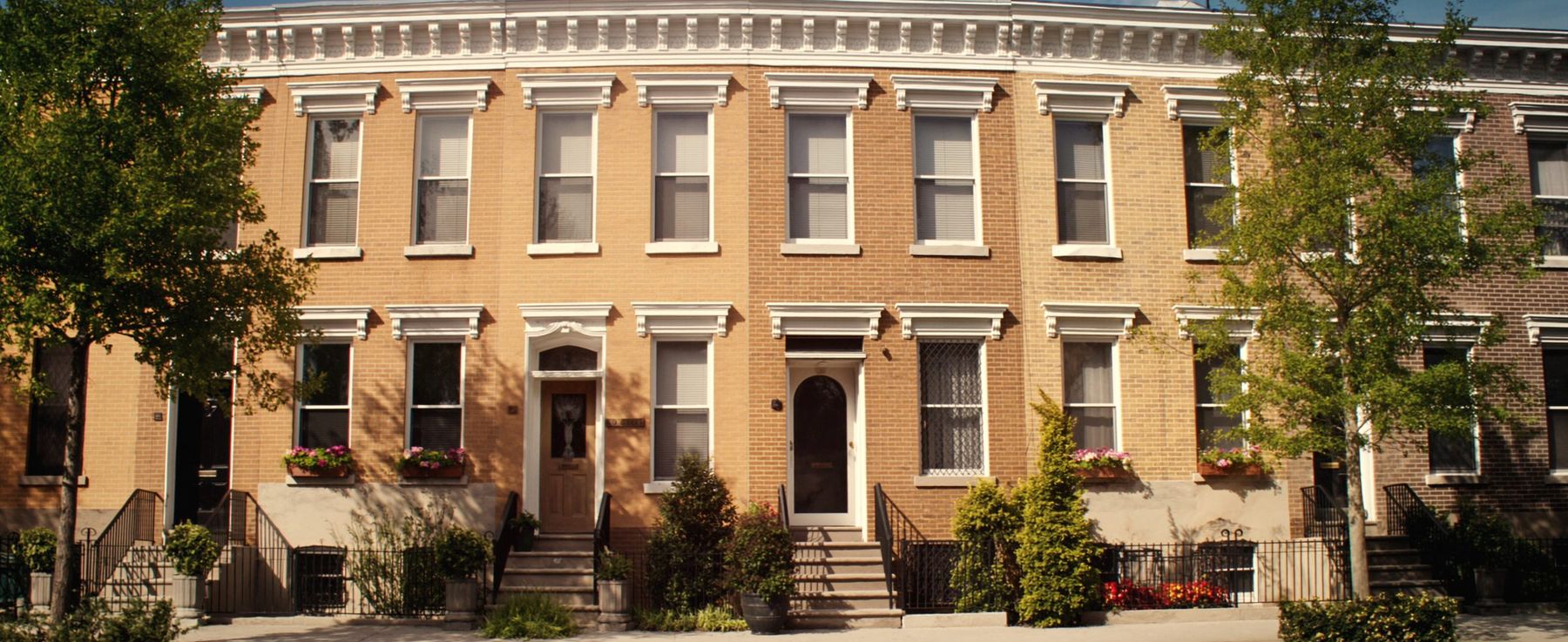 A row of attached yellow-brick Mathews Model Flats in Ridgewood, Queens