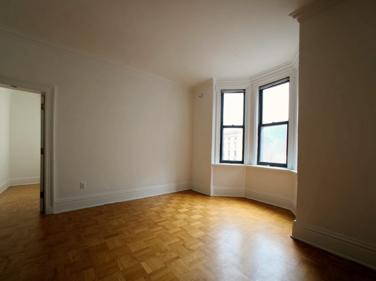 A large empty living and dining room with a bay window